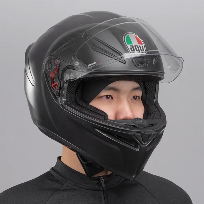 Mężczyzna z założoną czapką kolarską Rockbros YPP037 oraz kaskiem motocyklowym na szarym tle